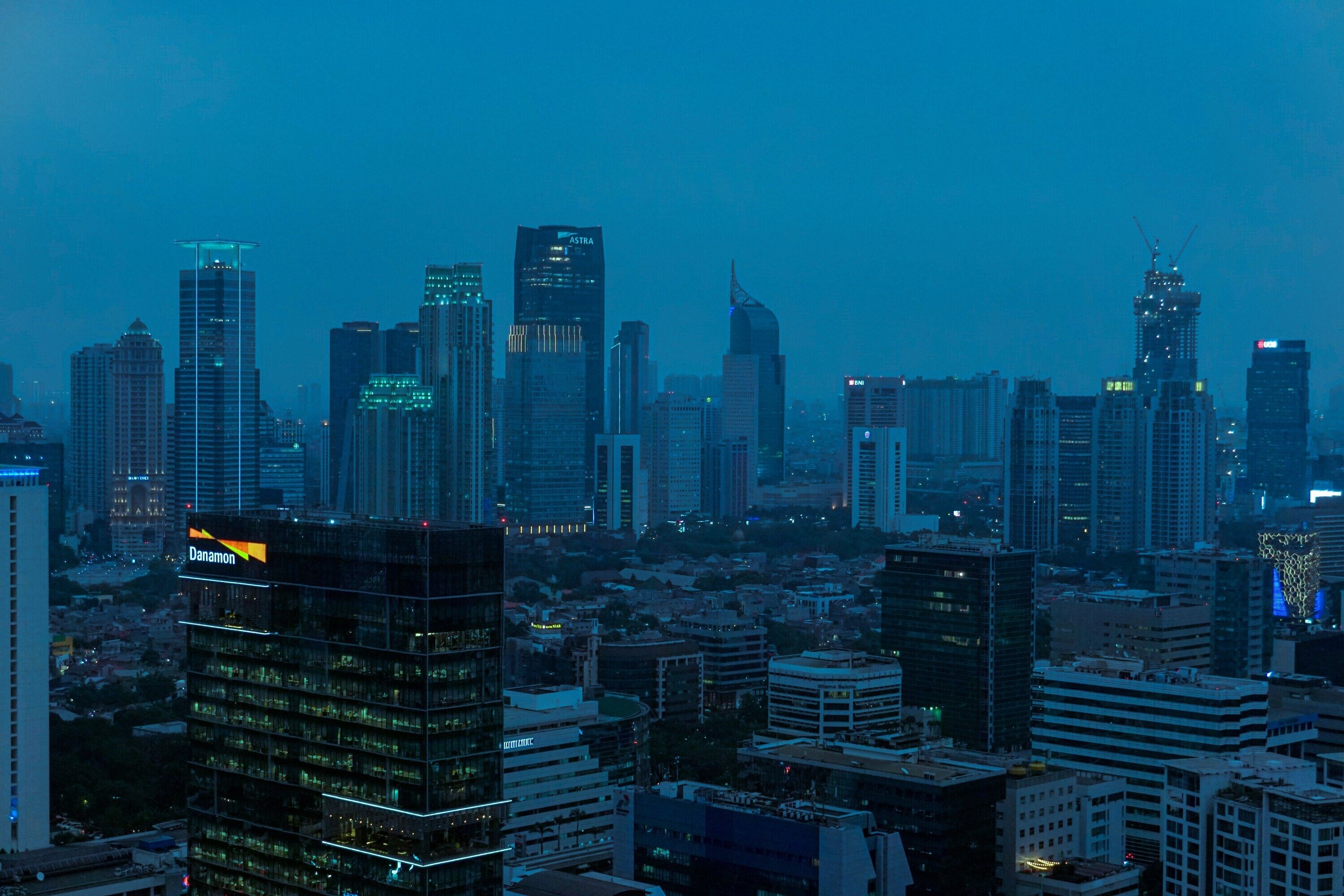 A cityscape at dusk with high-rise buildings, including a prominent hotel with a lit sign.