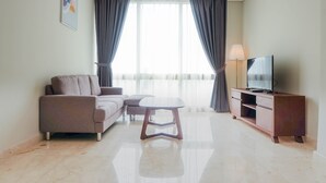 A modern living room with a sofa, a coffee table, a TV on a wooden cabinet, and a large window with curtains. - Posh 2BR at The Empyreal Condominium Epicentrum Apartment (Jakarta)