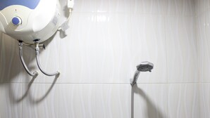 A shower area with a handheld showerhead and a fixed showerhead, both mounted on a tiled wall. - Minimalist Studio Gateway Ahmad Yani (Bandung)