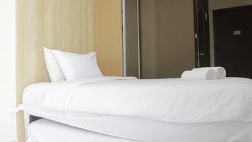 A neatly made bed with white linens and a rolled towel on top.