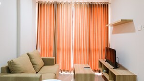 Una sala de estar moderna con un sofá, una mesa de centro y un televisor sobre un mueble de madera.