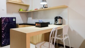 Cocina compacta con encimera de madera, una tetera, una cafetera y una bolsa de viaje sobre la encimera.