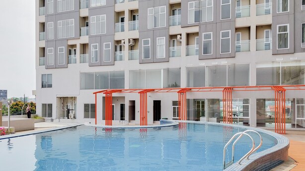 A modern building with a swimming pool, featuring a covered area with red railings. - Cozy Studio at Amazana Serpong Apartment (South Tangerang)