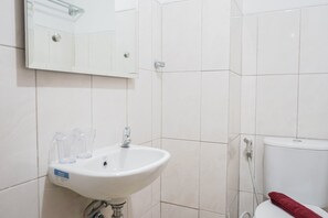 A bathroom with a white sink, a mirror, and a toilet. - Cozy Studio at Amazana Serpong Apartment (South Tangerang)