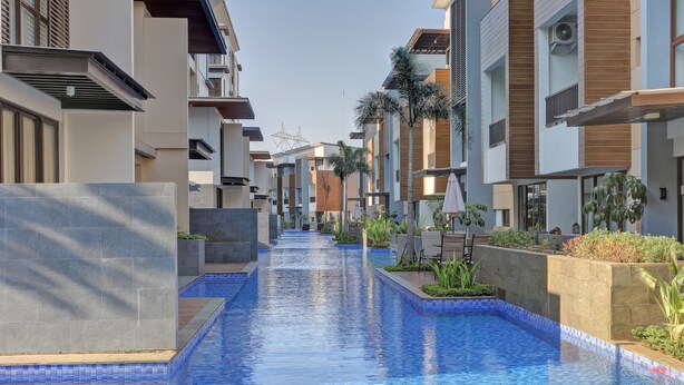 A modern residential building with a central swimming pool, surrounded by balconies and greenery. - Comfortable and Best Choice 1BR at Asatti Apartment (Pagedangan)