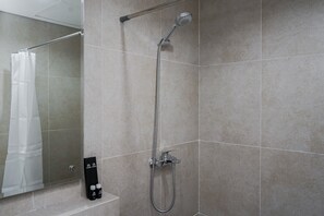 A modern bathroom with a shower, tiled walls, and a mirror. - Cozy 1BR at The Ayoma Apartment (South Tangerang)