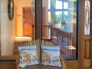 Una escalera con barandillas de madera y vistas a un balcón con mobiliario exterior.