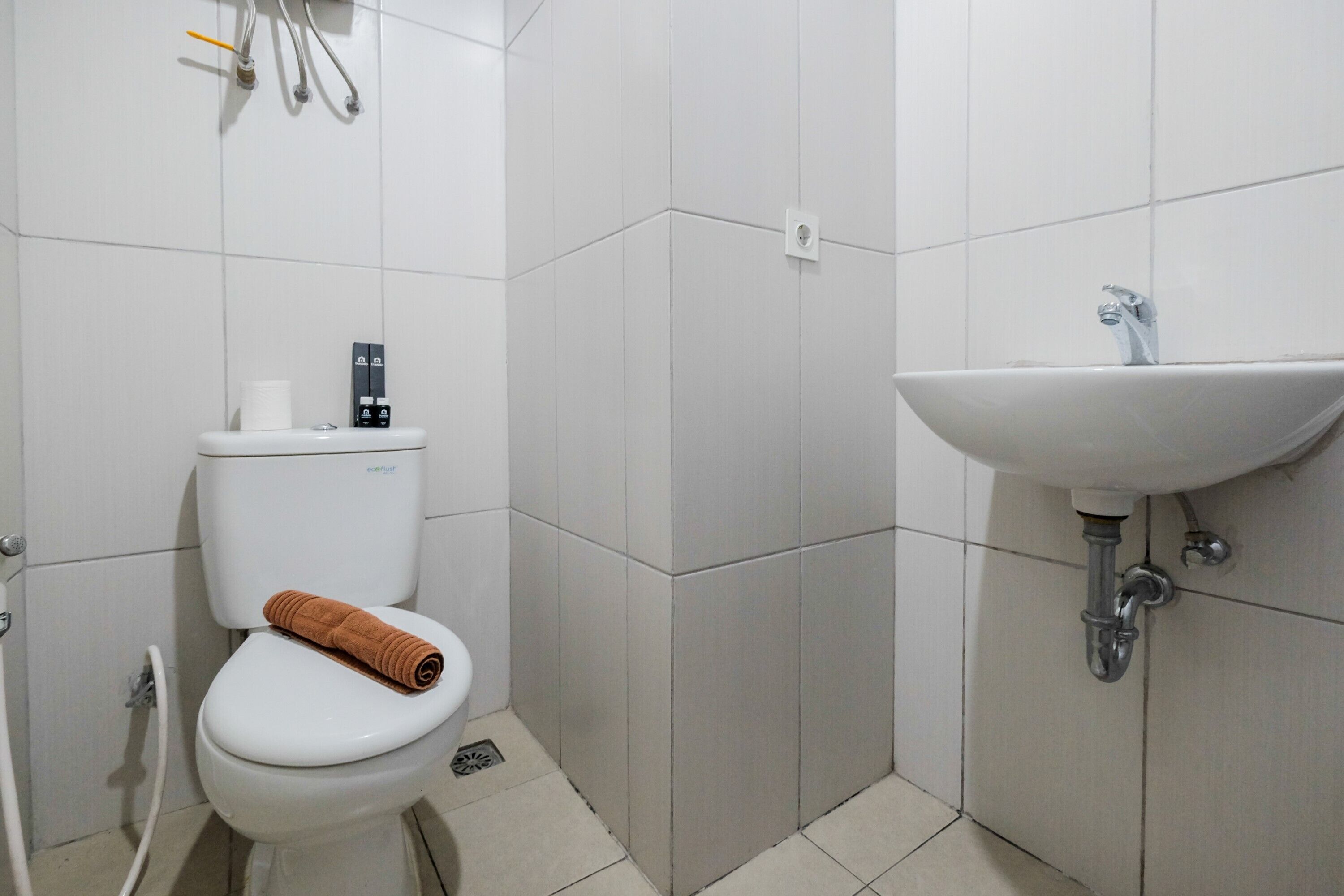 Une salle de bain avec des toilettes, un lavabo et une serviette posée sur les toilettes.