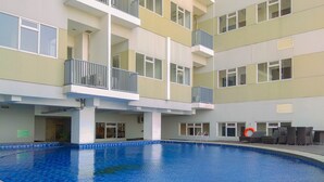 Ein mehrstöckiges Gebäude mit einem zentralen Schwimmbecken, Balkonen und Sitzgelegenheiten im Freien.