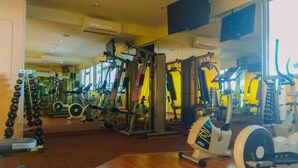 Ein Fitnessstudio mit verschiedenen Trainingsgeräten, darunter Kraftgeräte, Kurzhanteln und Cardiogeräte.