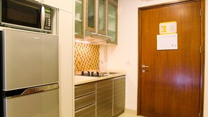 Eine kleine Küche mit integriertem Mikrowellenherd, Spüle und einer Holztür zum Schrank.