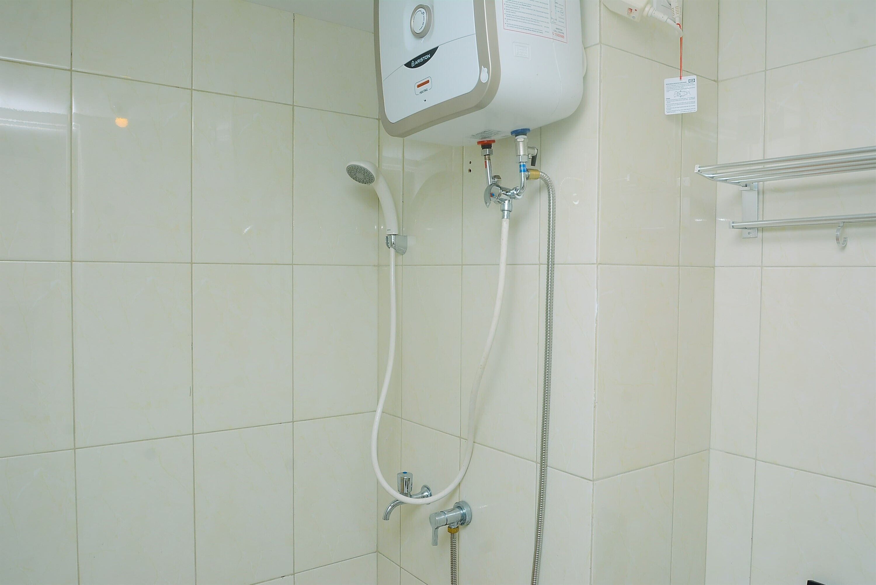 Un baño con ducha empotrada, ducha de mano y un perchero para toallas.