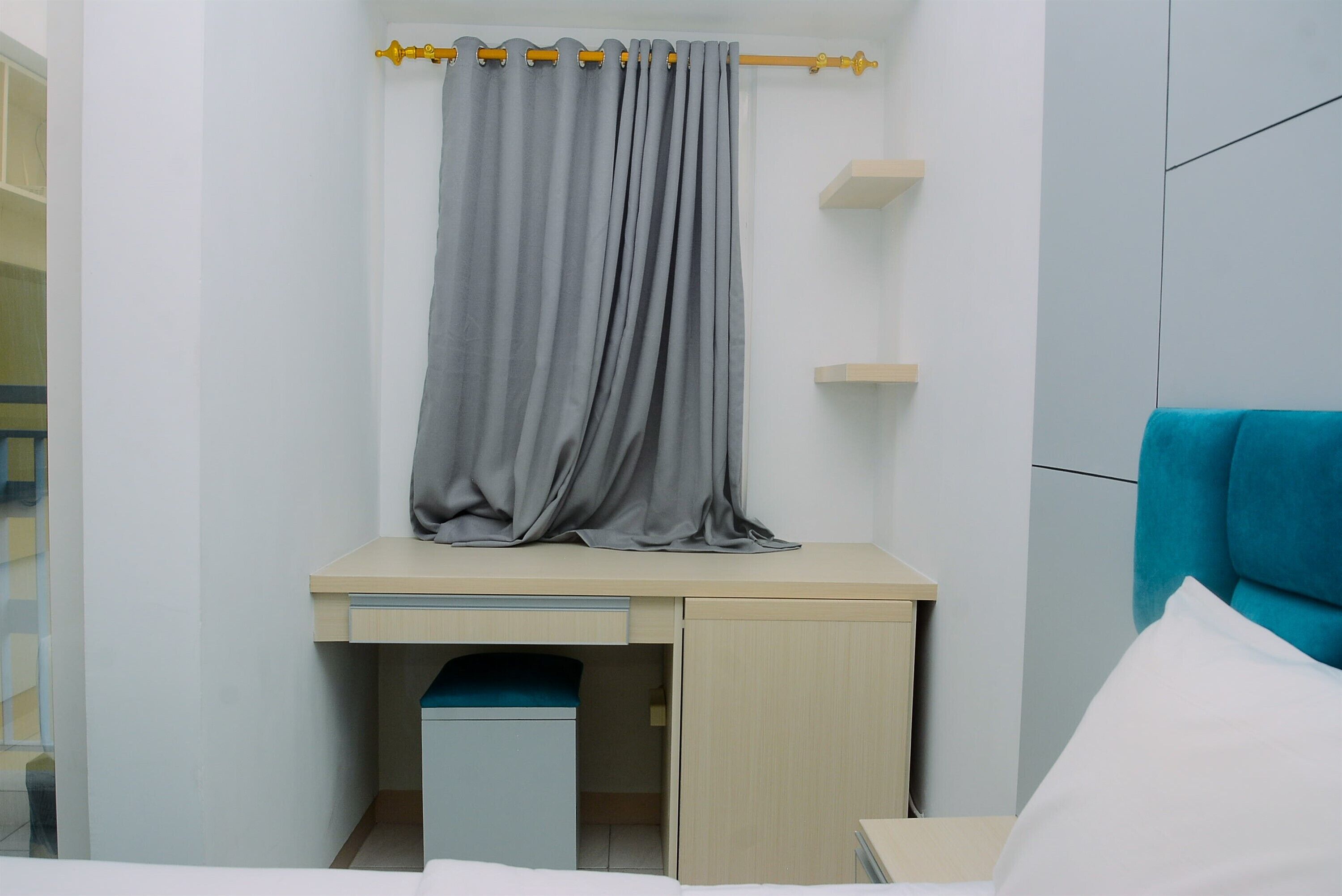 A bedroom with a bed, a desk, a chair, and a curtain.