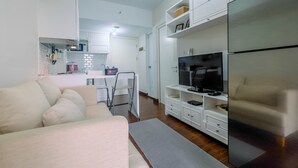 Uma sala de estar moderna com sofá, televisão e frigorífico embutido.