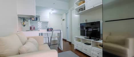 A modern living room with a sofa, a TV, and a built-in refrigerator.