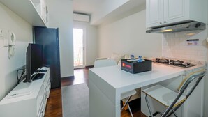 Uma cozinha moderna com armários brancos, fogão embutido e uma TV de tela plana sobre um balcão branco.
