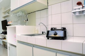 A kitchen with white cabinets, a sink, a toaster, and a dish rack. - Relax Studio Apartment @ Springlake Summarecon Bekasi (Bekasi)
