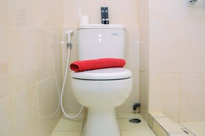 A toilet with a red towel on the seat, a flush handle, and a toilet paper holder. - Relax Studio Apartment @ Springlake Summarecon Bekasi (Bekasi)