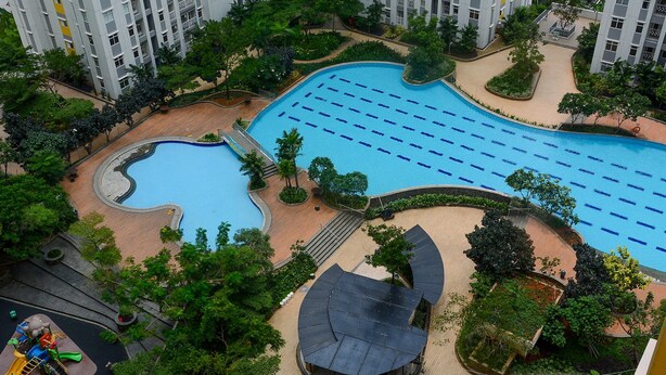 Un complexe résidentiel doté d’une piscine, entouré de verdure et comprenant un terrain de jeux.