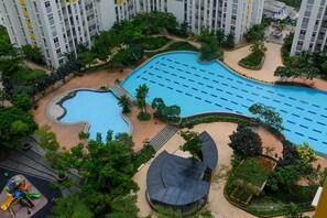 Un complejo residencial con piscina, rodeado de vegetación y un parque infantil.