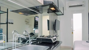 Une cuisine moderne dotée d’appareils électroménagers en acier inoxydable, d’une grande fenêtre et d’un téléviseur à écran plat fixé au mur.