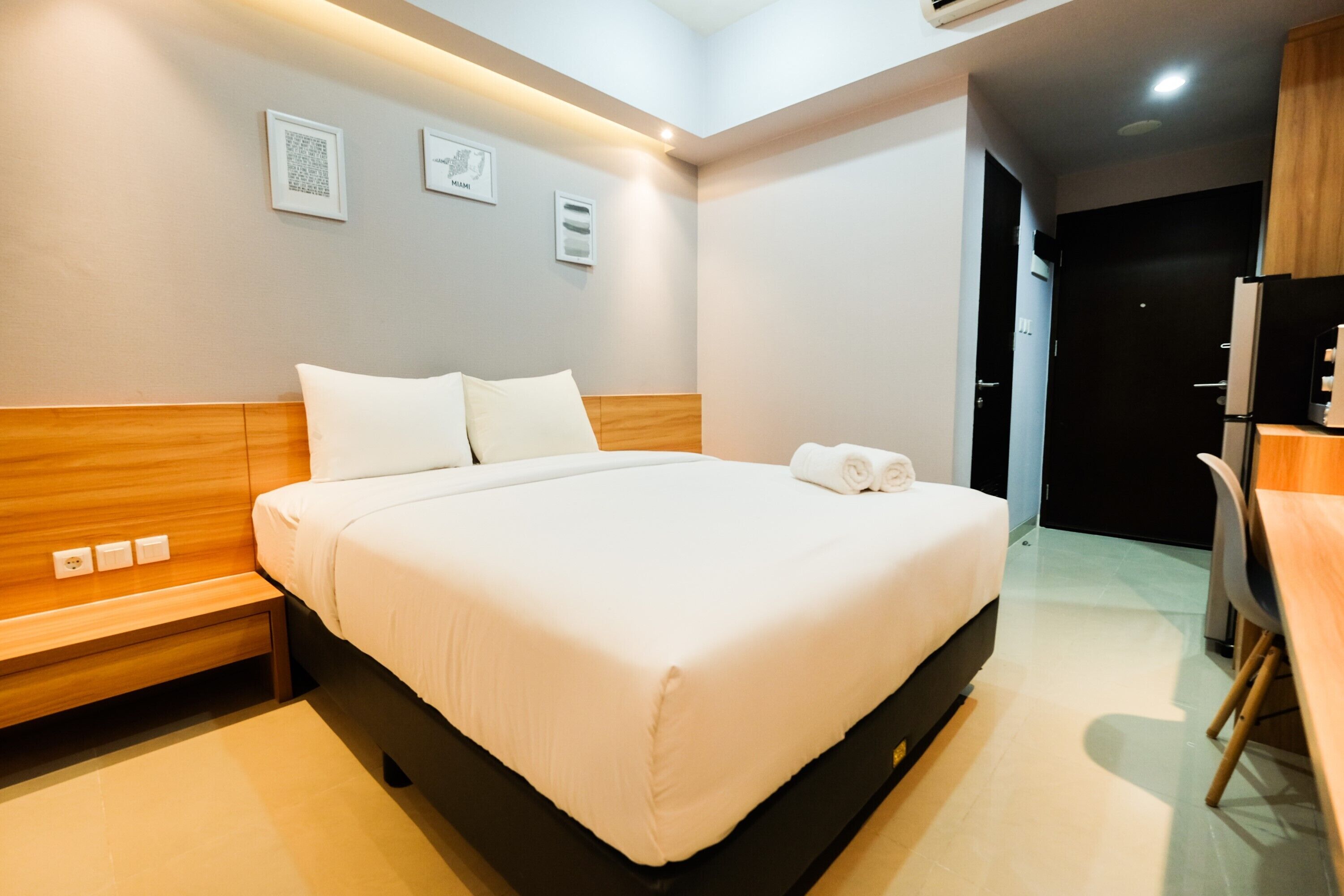 A modern hotel room with a large bed, bedside tables, a desk, and a chair.