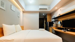 Et hotelværelse med en stor seng, et skrivebord med en computer, en stol og en aircondition.