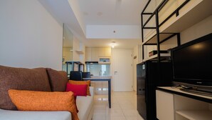 A modern living room with a sofa, television, and a kitchen area in the background. - Spacious 2BR Apartment at The Springlake Summarecon Bekasi (Bekasi)