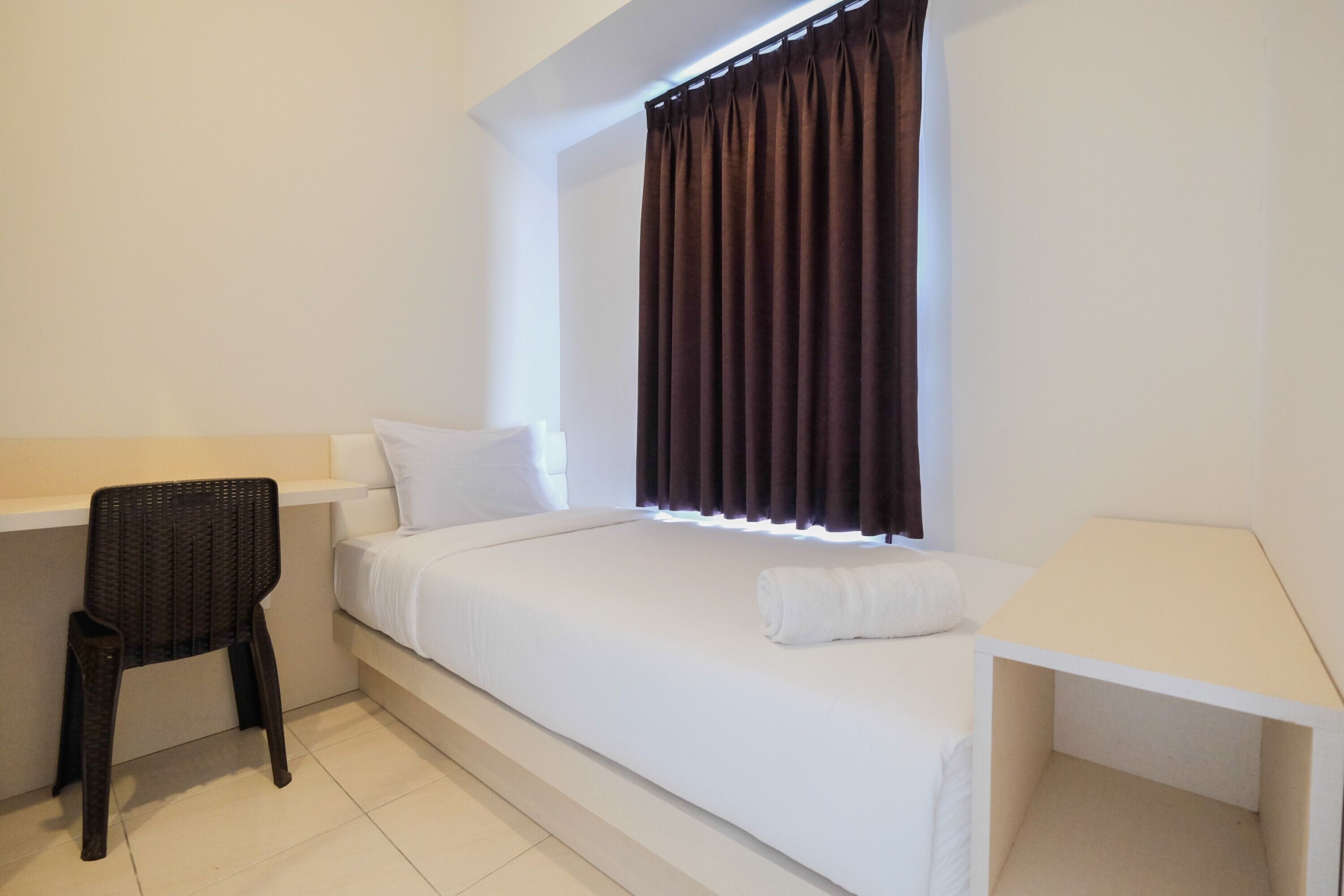 A small, clean room with a bed, a desk, and a chair.