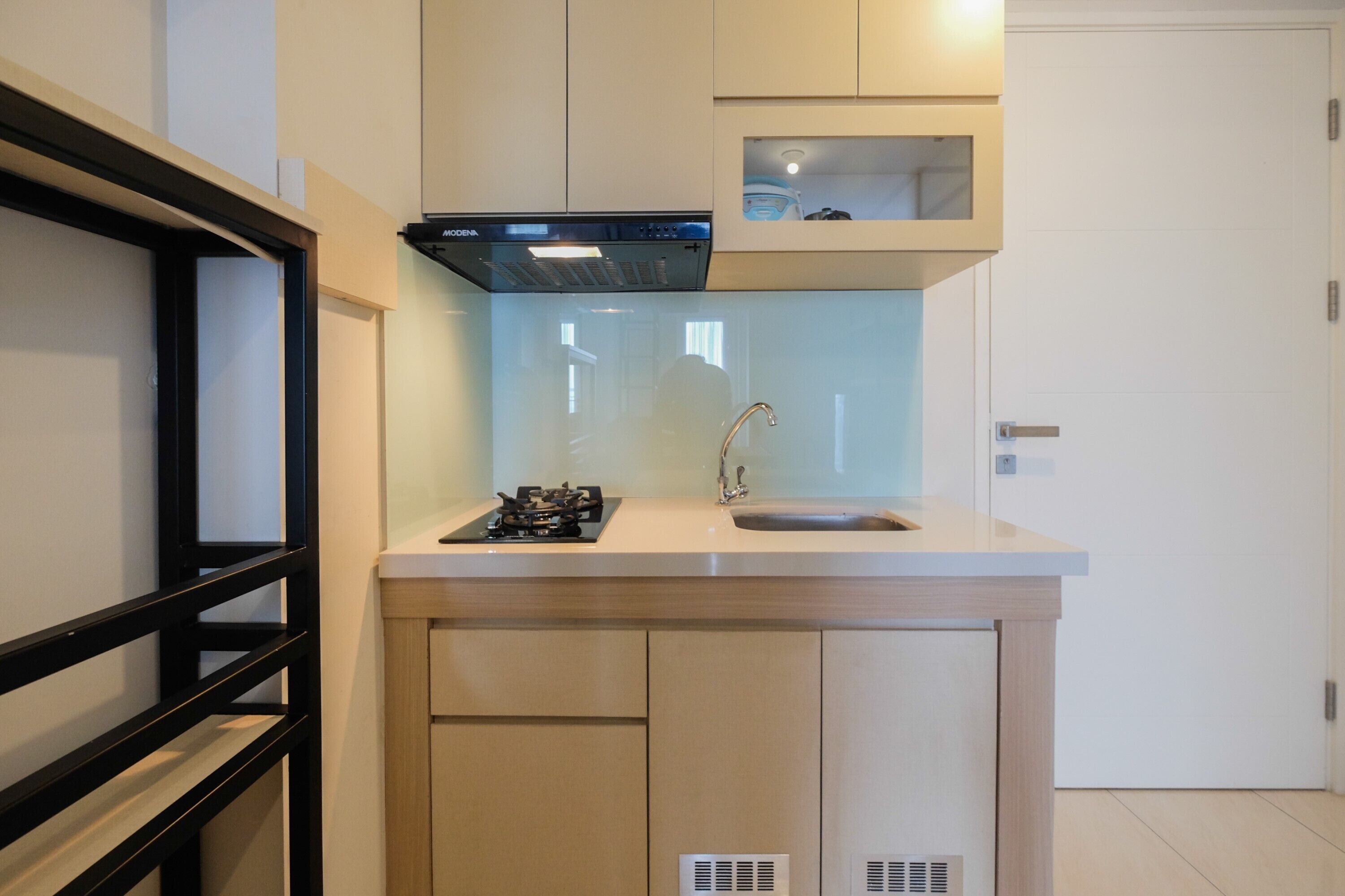A compact kitchen with a gas stove, sink, and integrated ventilation hood.