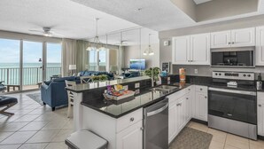 A modern kitchen with white cabinets, a central island, and a view of the ocean. - Majestic Sun A703*Gulf Views*Heated Pools/Hot Tubs*Beach Gear*Tennis (Destin)