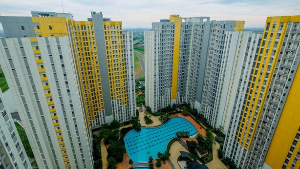 A high-rise residential building complex with multiple balconies, a central swimming pool, and surrounding greenery. - Comfortable and Lovely 2BR Apartment at Springlake Summarecon (Bekasi)