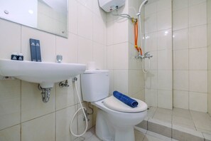 Une salle de bain avec un lavabo, des toilettes et une douche, le tout de couleur blanche.