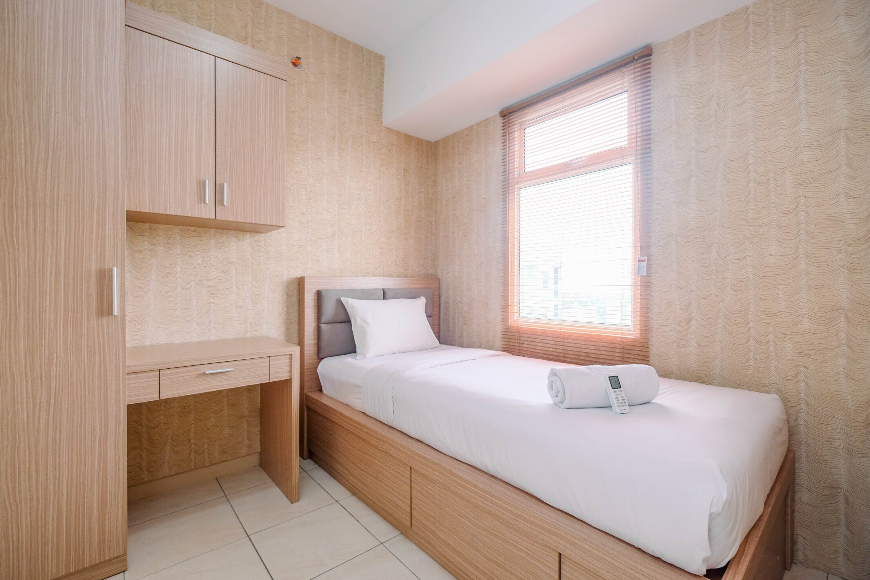 A bedroom with a bed, a desk, and a wardrobe.