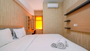 A hotel room with a bed, a desk, a chair, a mirror, and an air conditioning unit. - Comfortable and Lovely 2BR Apartment at Springlake Summarecon (Bekasi)