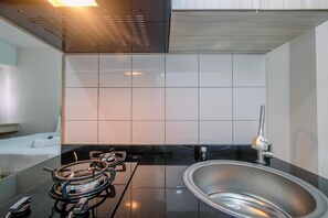 Una cocina moderna con estufa a gas, pileta de acero inoxidable y salpicadero de azulejos.