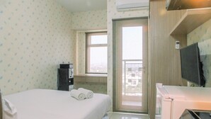 Quarto de hotel com cama, janela, televisão e minibar.