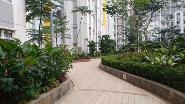A pathway flanked by lush greenery and modern buildings. - Relaxing 2BR Apartment at The Springlake Summarecon (Bekasi)