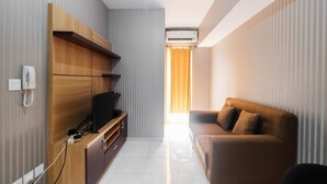 A modern living room with a wooden entertainment unit, a sofa, and a TV. - Relaxing 2BR Apartment at The Springlake Summarecon (Bekasi)