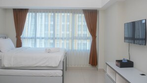 Habitación de hotel moderna con cama, televisión y una mesita con un paquete de agua embotellada.