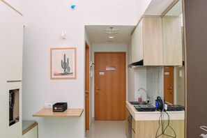 Une cuisine compacte avec une porte en bois, un petit plan de travail et une machine à café.
