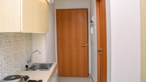 Une cuisine de taille réduite, équipée d’un évier, d’une cuisinière et de meubles de rangement en bois.