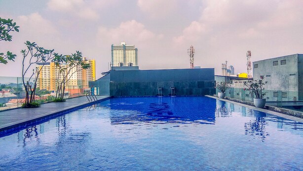 Une piscine sur le toit offrant une vue dégagée sur les bâtiments environnants et un ciel nuageux.