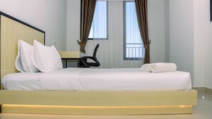 Une chambre d’hôtel moderne avec un grand lit, un bureau et deux fenêtres équipées de rideaux.