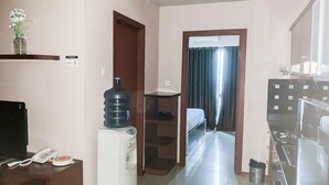 A hotel room with a bed, a water dispenser, a phone, and a large water bottle on a table.