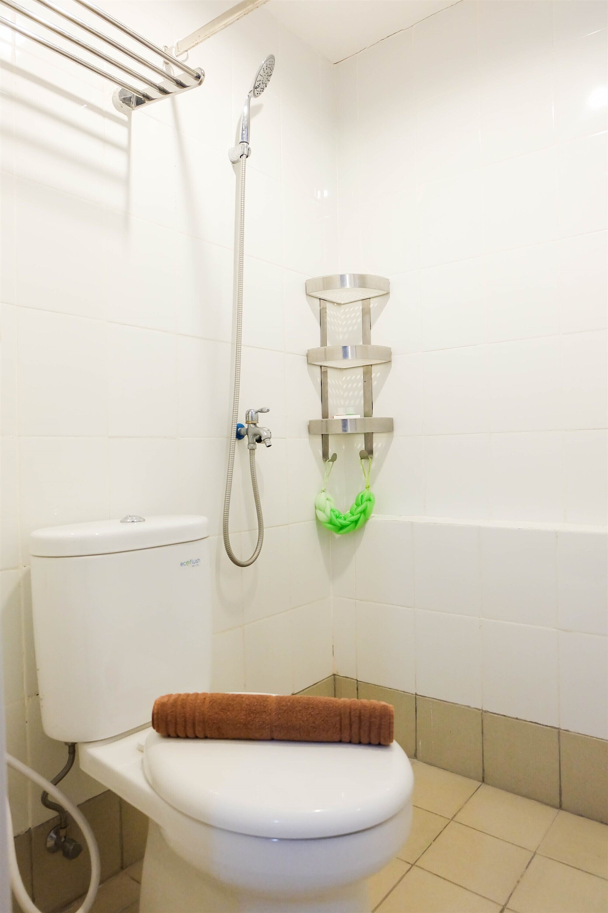 Une salle de bain équipée de toilettes, d’une douche et d’un porte-serviettes.