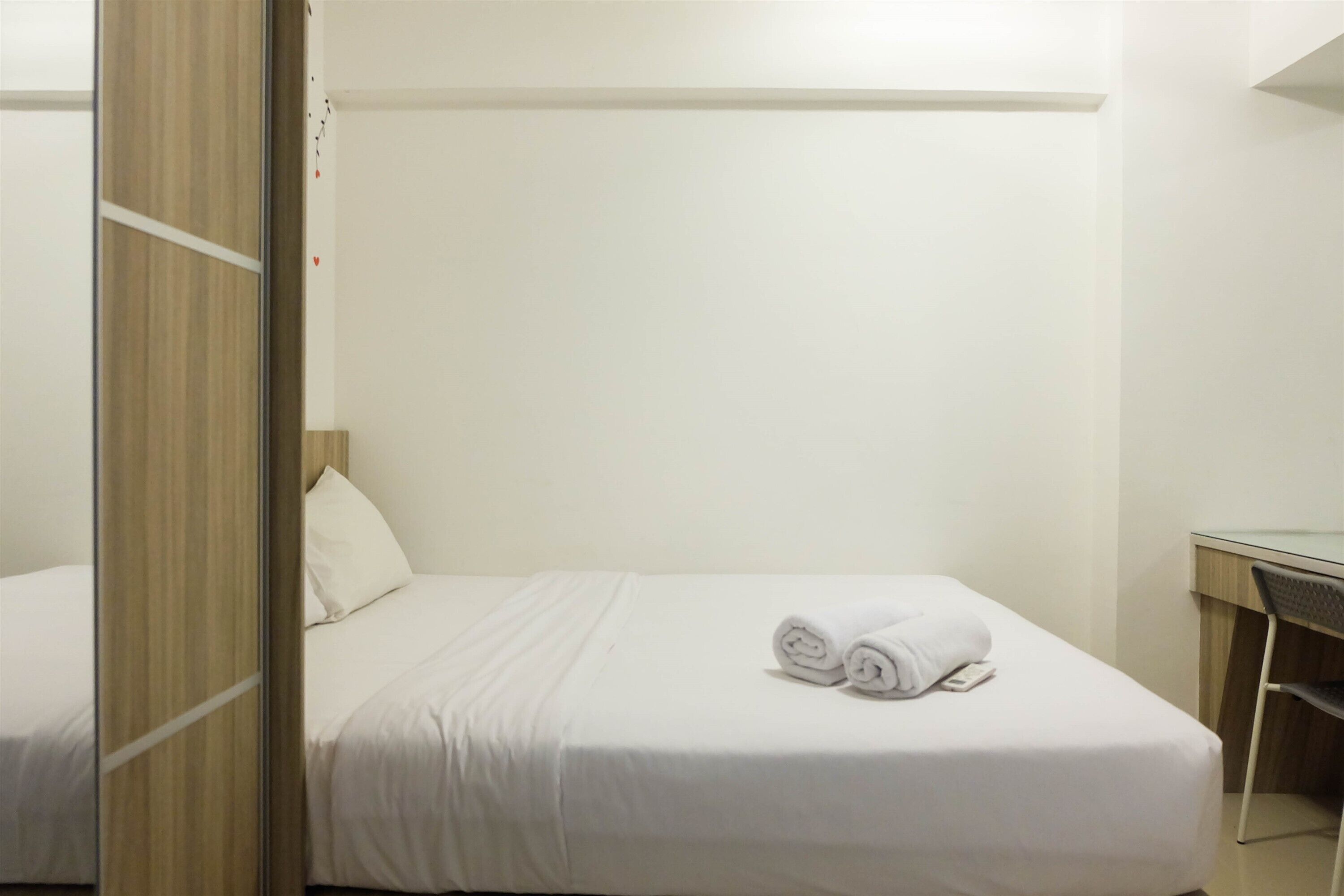 A hotel room with a single bed, a desk, and a chair.