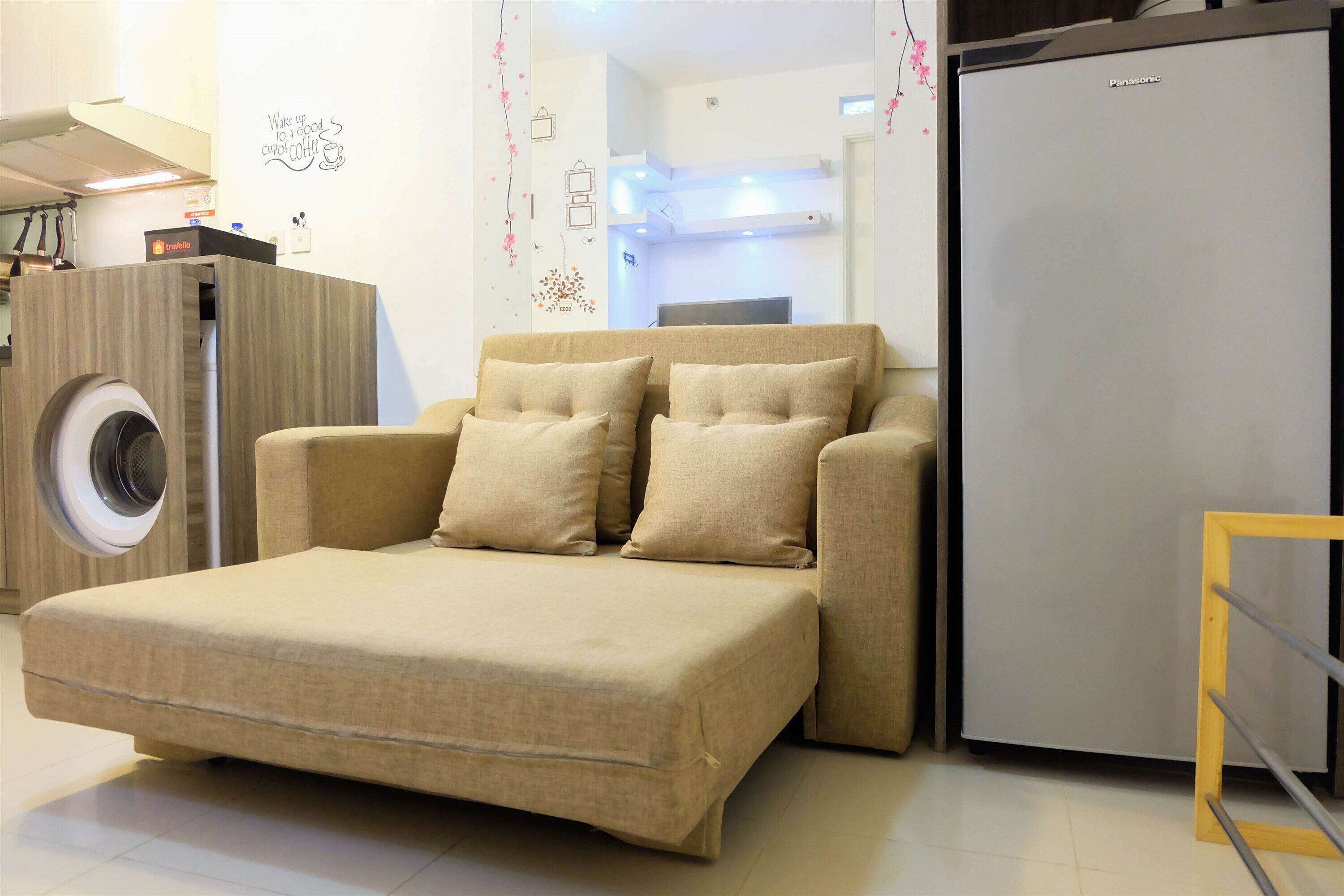Un espacio habitable compacto con sofá cama, lavadora y refrigerador.