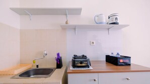 A kitchen with a sink, countertop, and cabinets. There is a coffee maker, a toaster, and a box of travel essentials on the countertop. - Simple Furnished Studio Apartment at Maple Park (Jakarta)