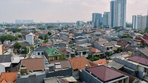 A densely packed urban residential area with a variety of building styles and a prominent high-rise building in the background. - Chic and Cozy 1BR Apartment at H Residence near MT Haryono (Jakarta)